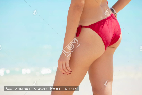 漂亮的年輕女子在海邊帶紅色泳裝