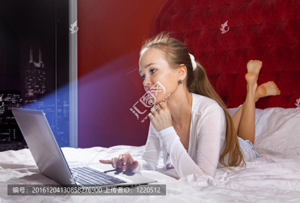 床上的年輕女人用筆記本電腦