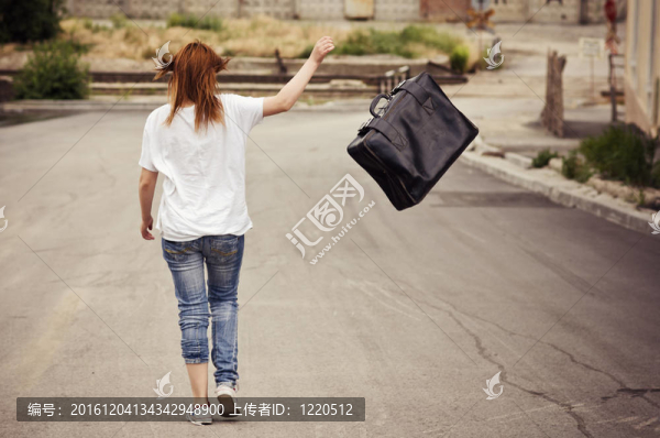 年輕的女孩把手提箱扔在街上