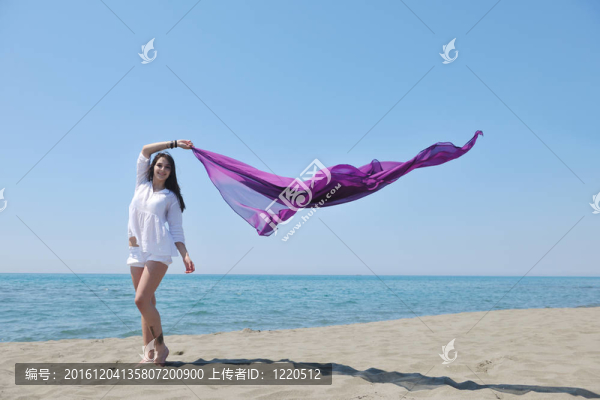 美麗的年輕女子在海灘與圍巾