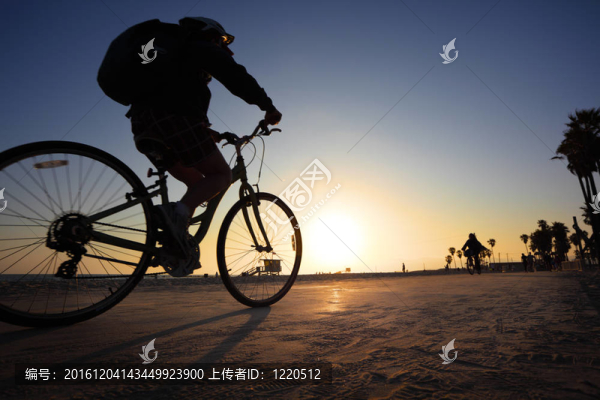 騎自行車的身影騎在日落海灘