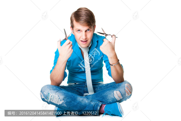 年輕漂亮的男理發(fā)師穿著藍(lán)色襯衫和白色領(lǐng)帶夾著兩個剪刀坐在白色背景上