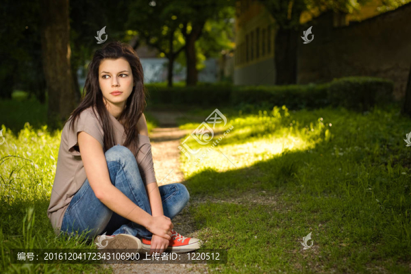 美麗的年輕女人坐在公園里悠閑的肖像。