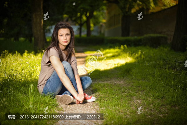 美麗的年輕女人坐在公園里悠閑的肖像。