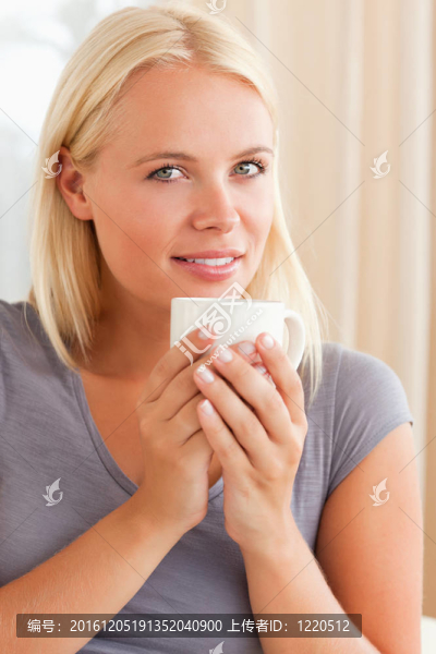 一個冷靜的女人坐在沙發(fā)上喝著一杯茶