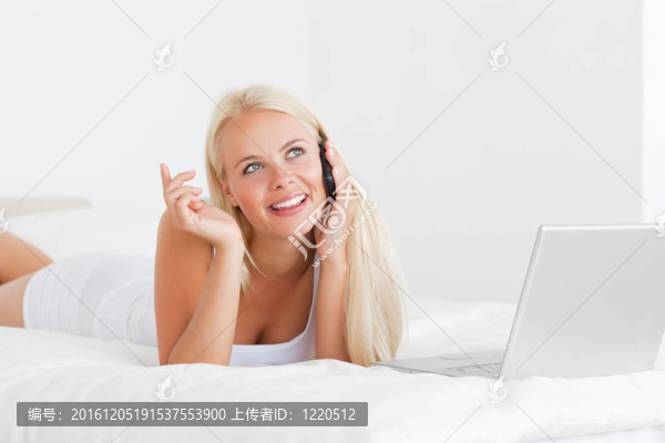 微笑的女人用筆記本對著電話說話