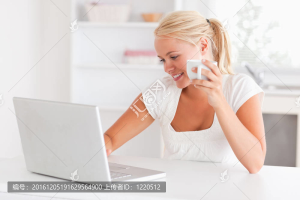 可愛(ài)的女人在使用筆記本電腦時(shí)喝了一杯茶