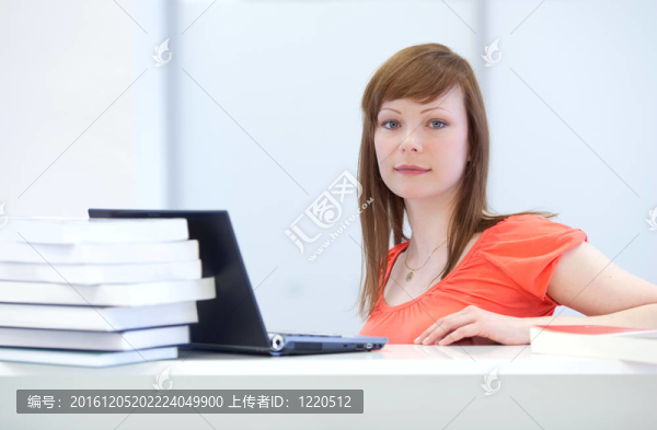 一個(gè)漂亮的年輕婦女在圖書館使用筆記本電腦的肖像