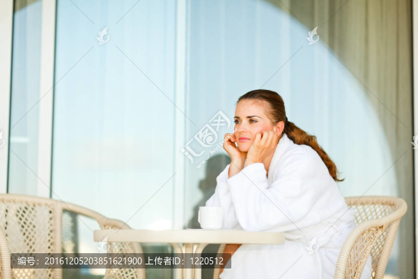 在浴袍坐在露臺上的美麗的女人，在表