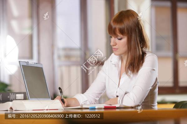 在圖書館-年輕的女學(xué)生與筆記本電腦和書籍在高中圖書館工作