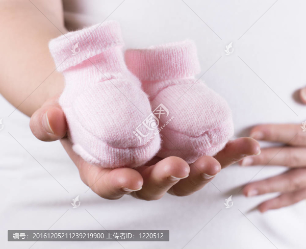 孕婦抱著粉紅色的鞋對女嬰