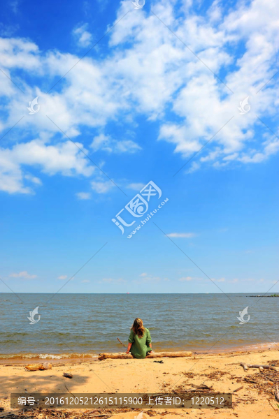 一個(gè)女孩在夏天的海灘上仰望著云朵