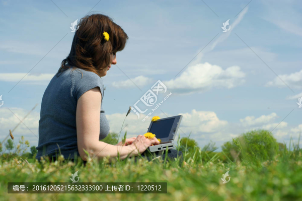 女人在筆記本在草地上打字