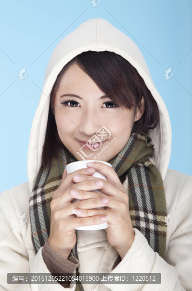 年輕的女人穿著冬天的衣服，端著咖啡杯