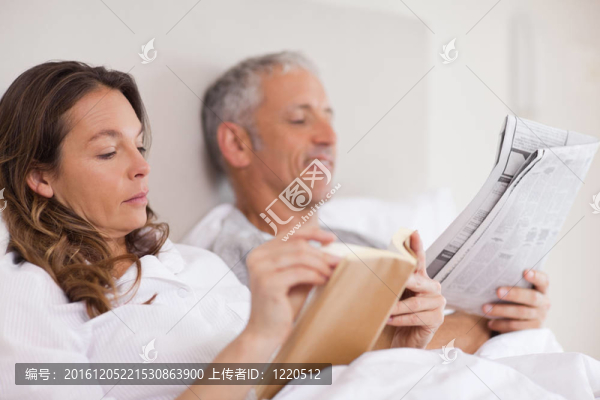 女人讀一本書，而她的丈夫正在看報紙