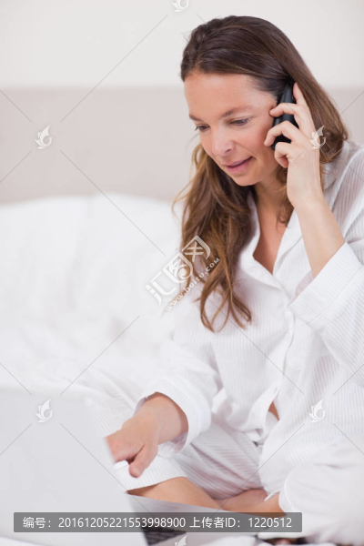 而在她的臥室打電話使用筆記本電腦的一個(gè)安靜的女人肖像