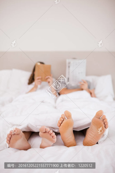 女人讀一本書(shū)，而她的同伴閱讀在他們的臥室里的新聞人物