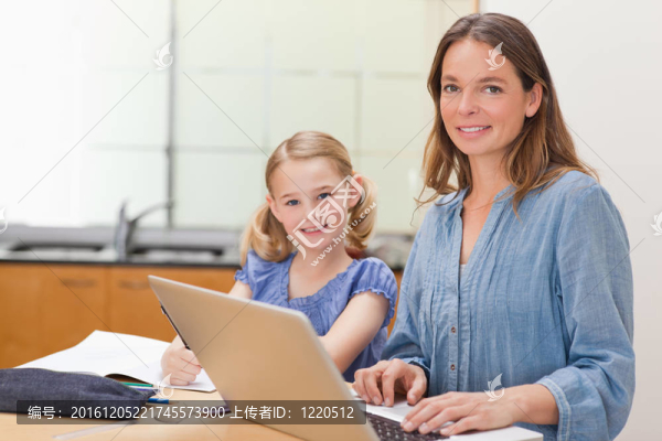女孩在做作業(yè)，她媽媽正在與筆記本電腦