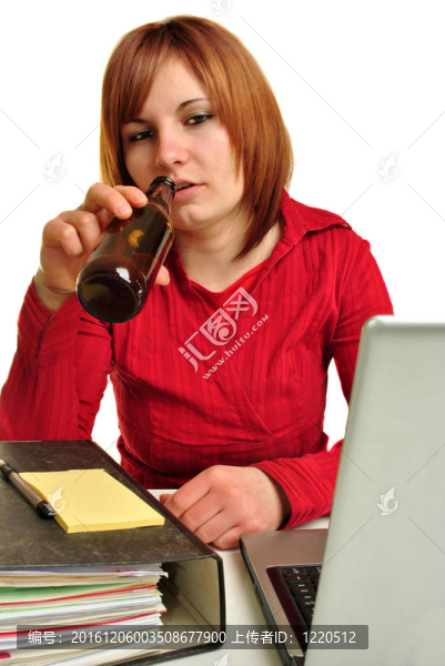 一個年輕女人在她的辦公桌旁喝酒