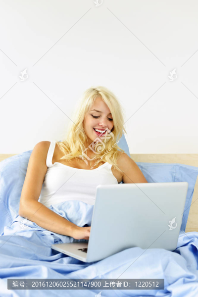 快樂的女人在床上與筆記本電腦