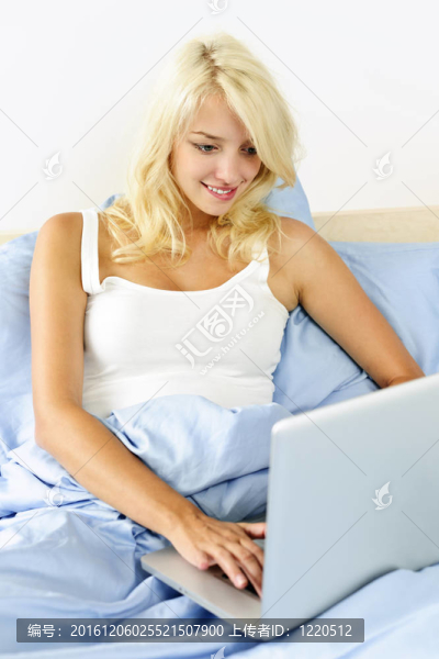 女人坐在床上用筆記本電腦