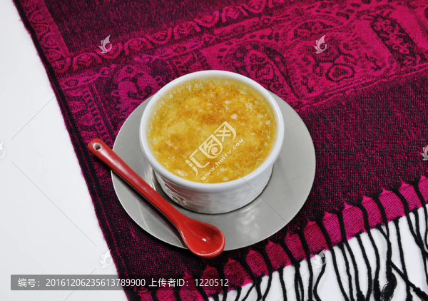 小蛋奶凍在以白色為背景的印度尼西亞桌布紅色陶瓷勺子
