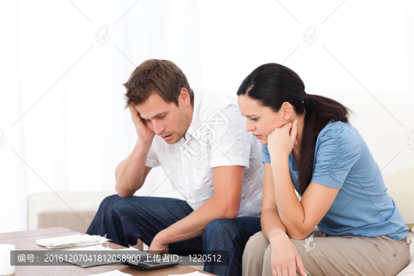 憂慮的夫婦看著他們的賬單在沙發(fā)上