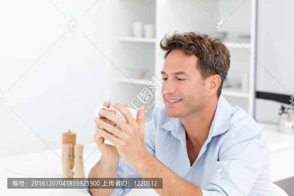 迷人的男子坐在桌旁喝咖啡