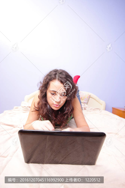十幾歲的女孩在床上看著她的筆記本電腦