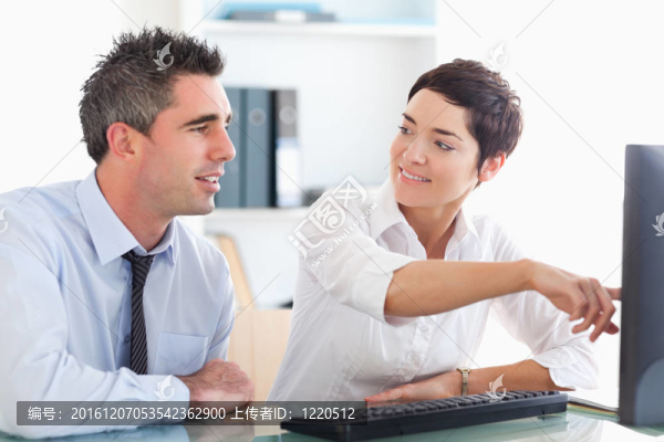 辦公室職員指著屏幕上的東西給她的同事