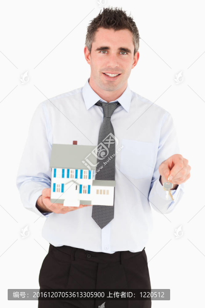 拿著鑰匙和微型房子的商人