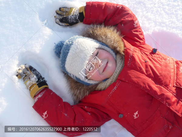 男孩穿著明亮的冬衣躺在雪地上