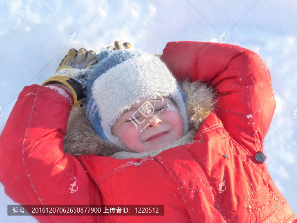 男孩穿著明亮的冬衣躺在雪地上