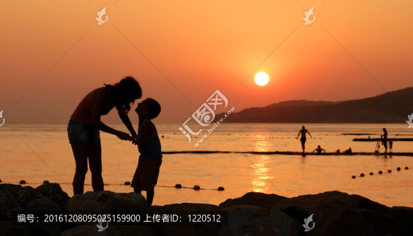 剪影的孩子和他的母親在橙色的夕陽(yáng)在海上