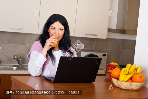 在廚房里喝橙汁的女人