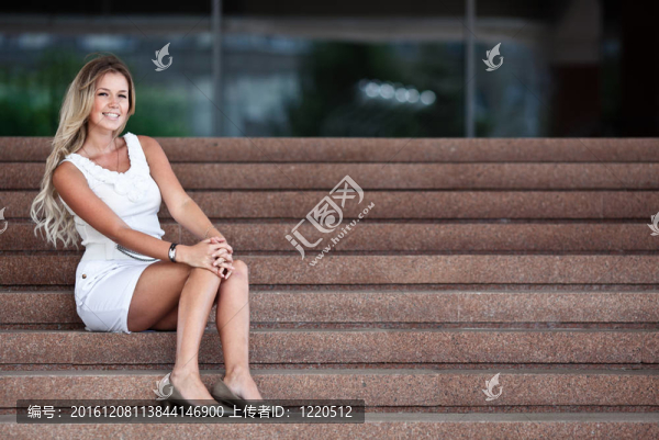 迷人的年輕女子坐在辦公樓的樓梯上