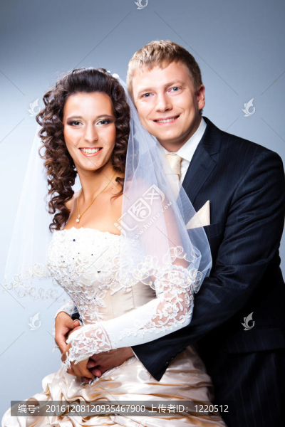 年輕優(yōu)雅的迷戀剛結(jié)婚的新娘和新郎抱著灰色背景的工作室肖像