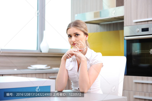 年輕漂亮的金發(fā)女人坐在廚房的椅子上