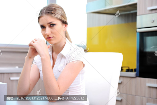 年輕漂亮的金發(fā)女人坐在廚房的椅子上