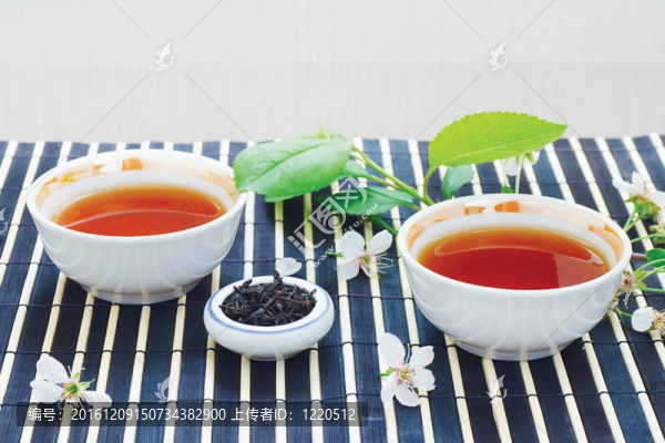 兩杯茶；盛滿茶葉的葉子和櫻桃，還有竹葉上的靜物桌布