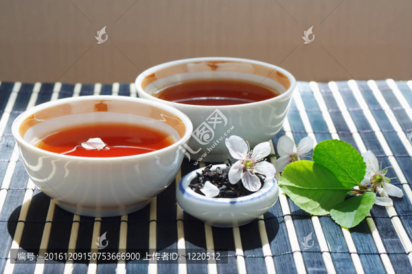 兩杯茶；盛滿茶葉的葉子和櫻桃，還有竹葉上的靜物桌布