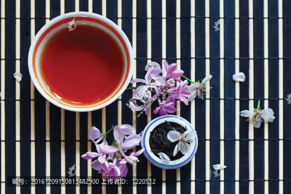 一杯茶；一罐茶葉和丁香花在竹臺布上還活著