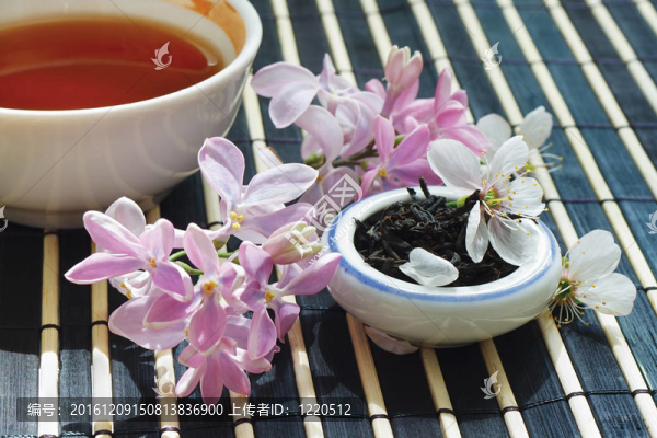 一杯茶；一罐茶葉和丁香花在竹臺布上還活著