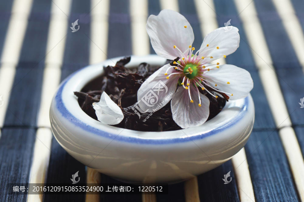 一罐茶葉和櫻花在竹桌布上依然存在