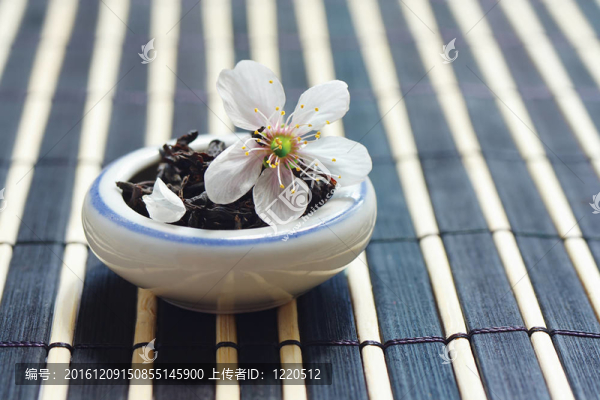 一罐茶葉和櫻花在竹桌布上依然存在
