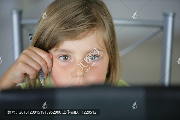 小女孩坐在廚房桌子旁，手里拿著筆記本電腦