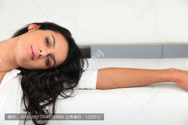 黑頭發(fā)懶洋洋地靠在白色沙發(fā)上的女人