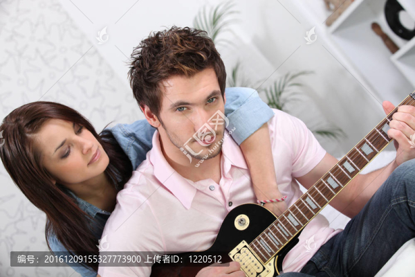 女人擁抱他的男朋友，而他彈吉他