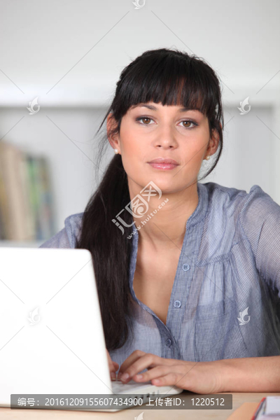 年輕的泰然自若的女人坐在筆記本電腦上