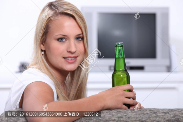 年輕的女人在家里有一瓶未開封的啤酒
